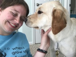 Colleen laughs as Golden yellow puppy Joplin noses her cheek